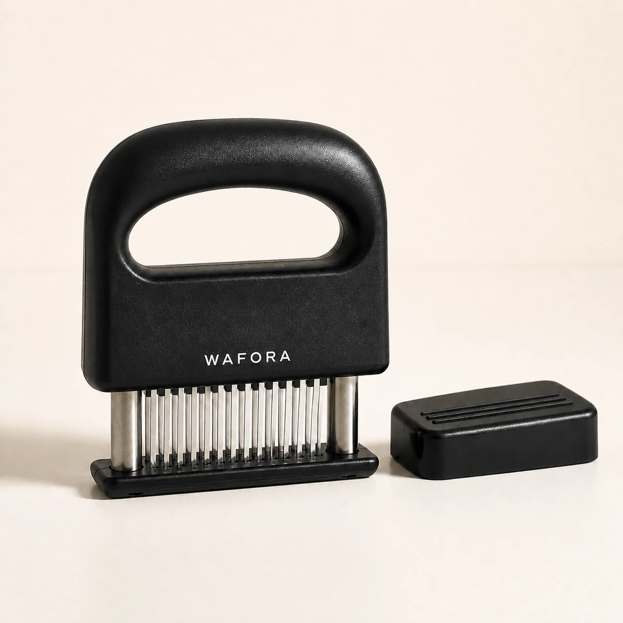 Black WAFORA TenderPress 48-blade meat tenderizer with protective cover on a warm ivory background
