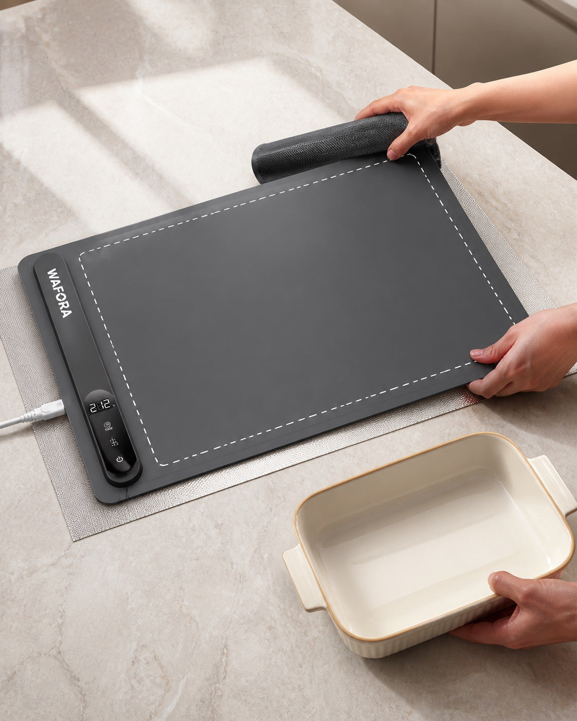 WAFORA™ TableWarm XL roll-up food warming mat displayed on a countertop with hands preparing a dish.