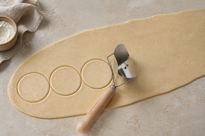 Top view of the WAFORA dumpling skin cutter rolling through dough to create round wrappers