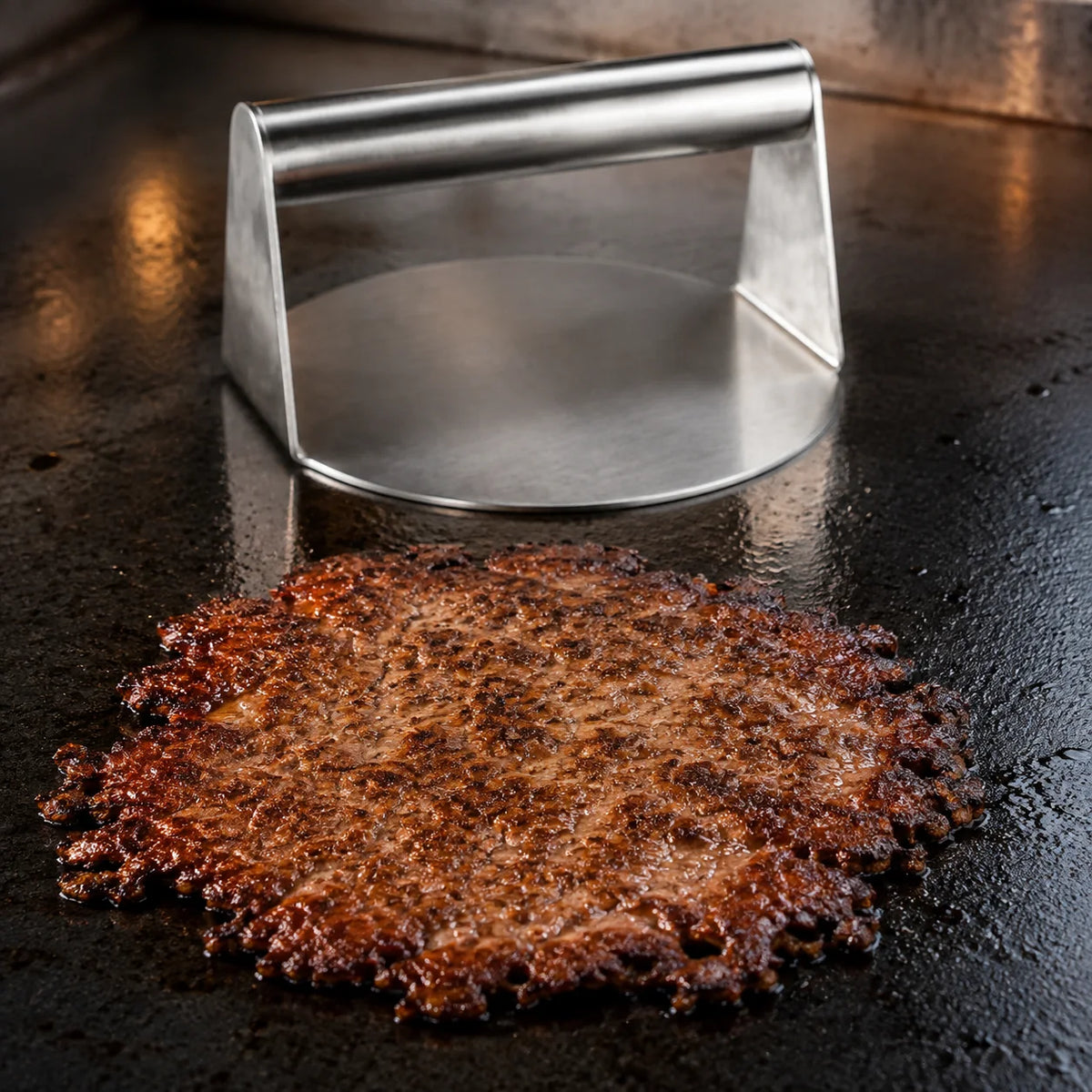 Thin smash burger patty with crisp browned edges beside the WAFORA SmashPress