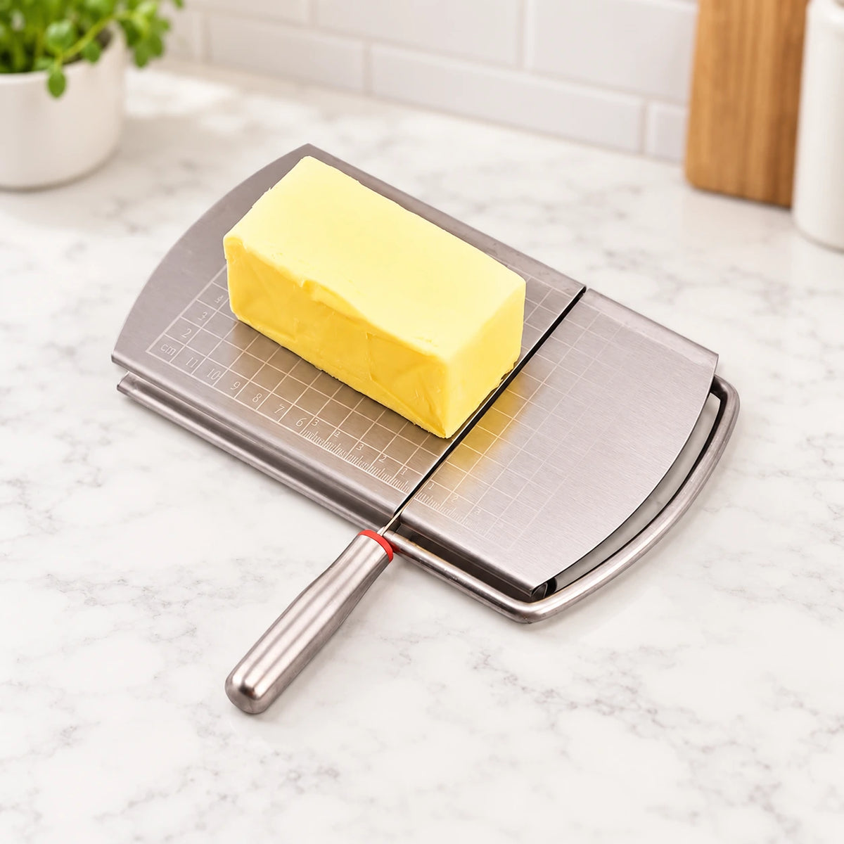 Cheese block positioned on the marked stainless steel board with the blade lowered