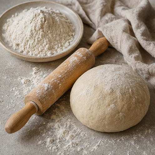 Fresh dough being rolled into an even sheet on a floured work surface