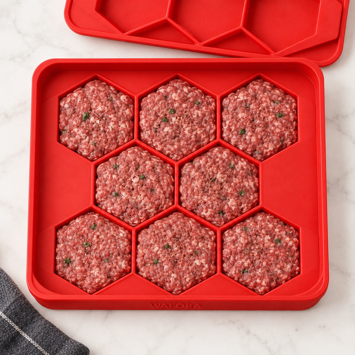 Overhead view of eight uniform hexagonal burger patties in the red WAFORA BurgerBatch tray.