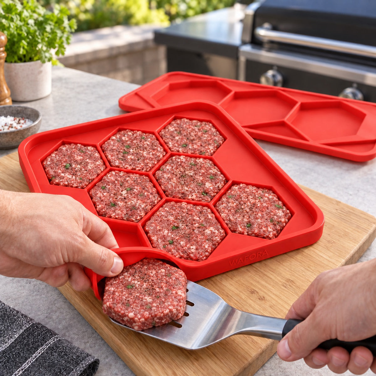 Hands peeling the flexible BurgerBatch tray away from one hexagonal patty before cooking.