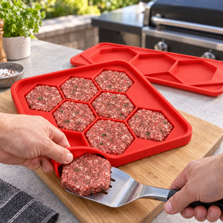Hands peeling the flexible BurgerBatch tray away from one hexagonal patty before cooking.