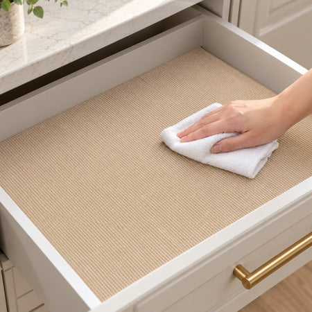 A hand wiping an installed Khaki drawer liner with a damp white cloth
